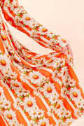 Close up of Young girl in bamboo twirl dress wearing a bamboo Twirl dress with orange and white stripe, with white daisy's on top  and the reverse side a bright orange against a beige background