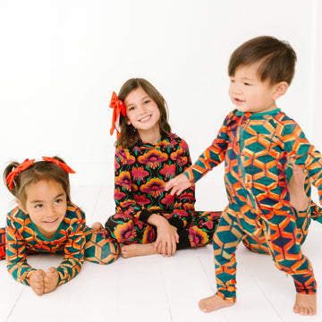 Three children wearing colorful geometric-patterned outfits on a white background