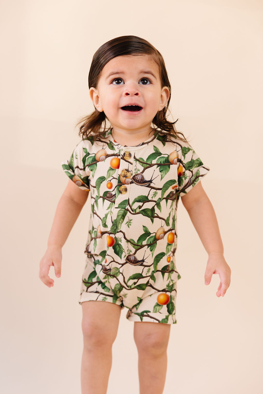Kid wearing snail shortie and apricot pattern short sleeve and short Romper, Henley buttons