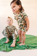 Two kids in matching snail pattern on green backing of snail pattern bamboo blanket