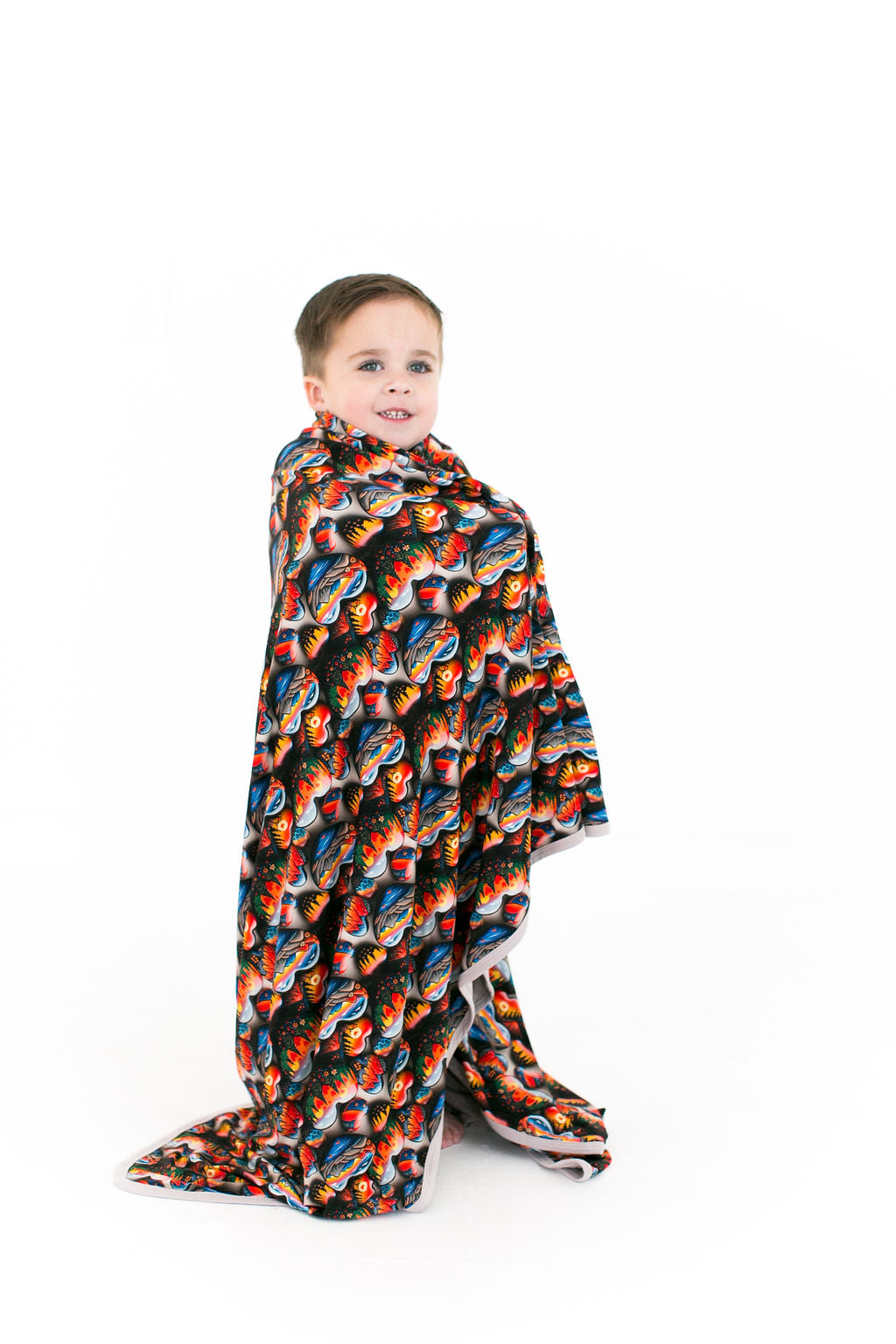 A toddler draping the wild at heart bamboo blanket over his body