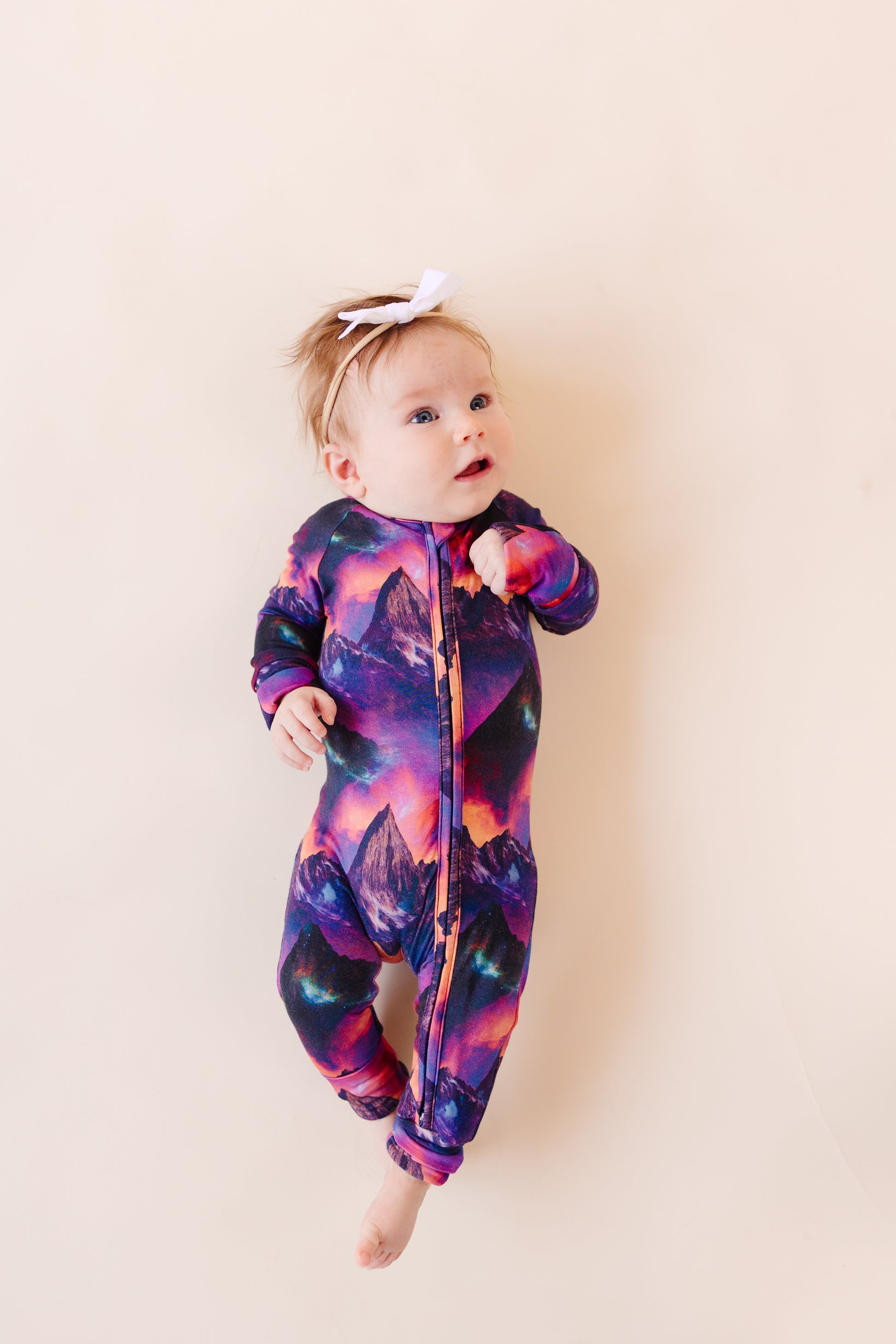Baby wearing a colorful galaxy mountain bamboo convertible romper from Bronze moon clothing co