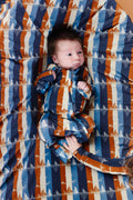 Baby lying on a colorful striped blanket