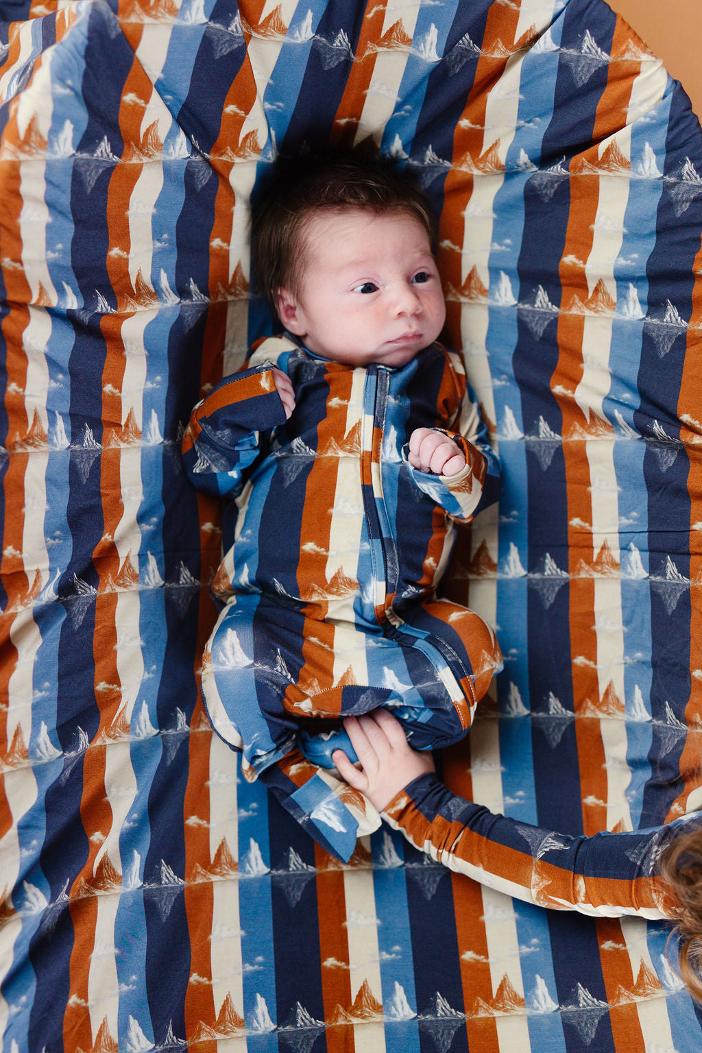 Baby lying on a colorful striped blanket