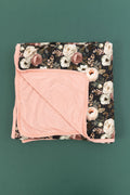 Reverie floral bamboo blanket with cream, blush, and dusty rose flowers on a dark green background