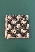 Reverie floral bamboo blanket with cream, blush, and dusty rose flowers on a dark green background